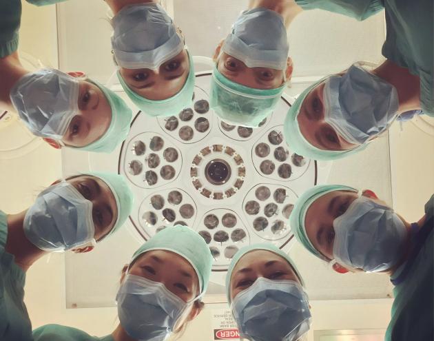 A group of medical professionals prepare a person for surgery.