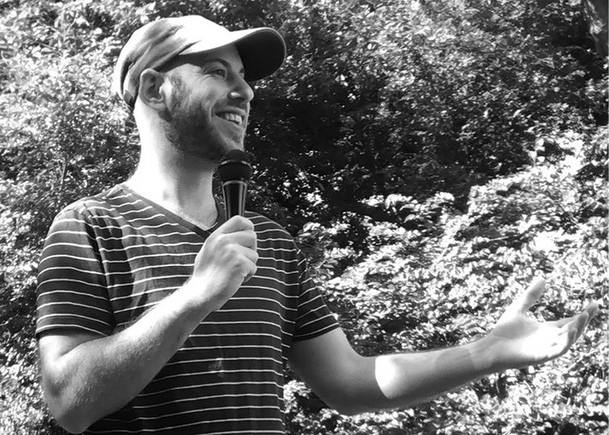 man in hat and v-neck t-shirt doing stand-up