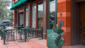 a green sign in front of the entryway of a brick building