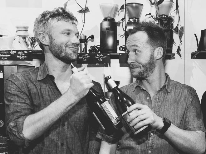 two men holding bottle of wine