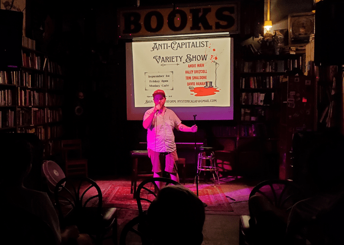 man on stage with powerpoint presentation behind him