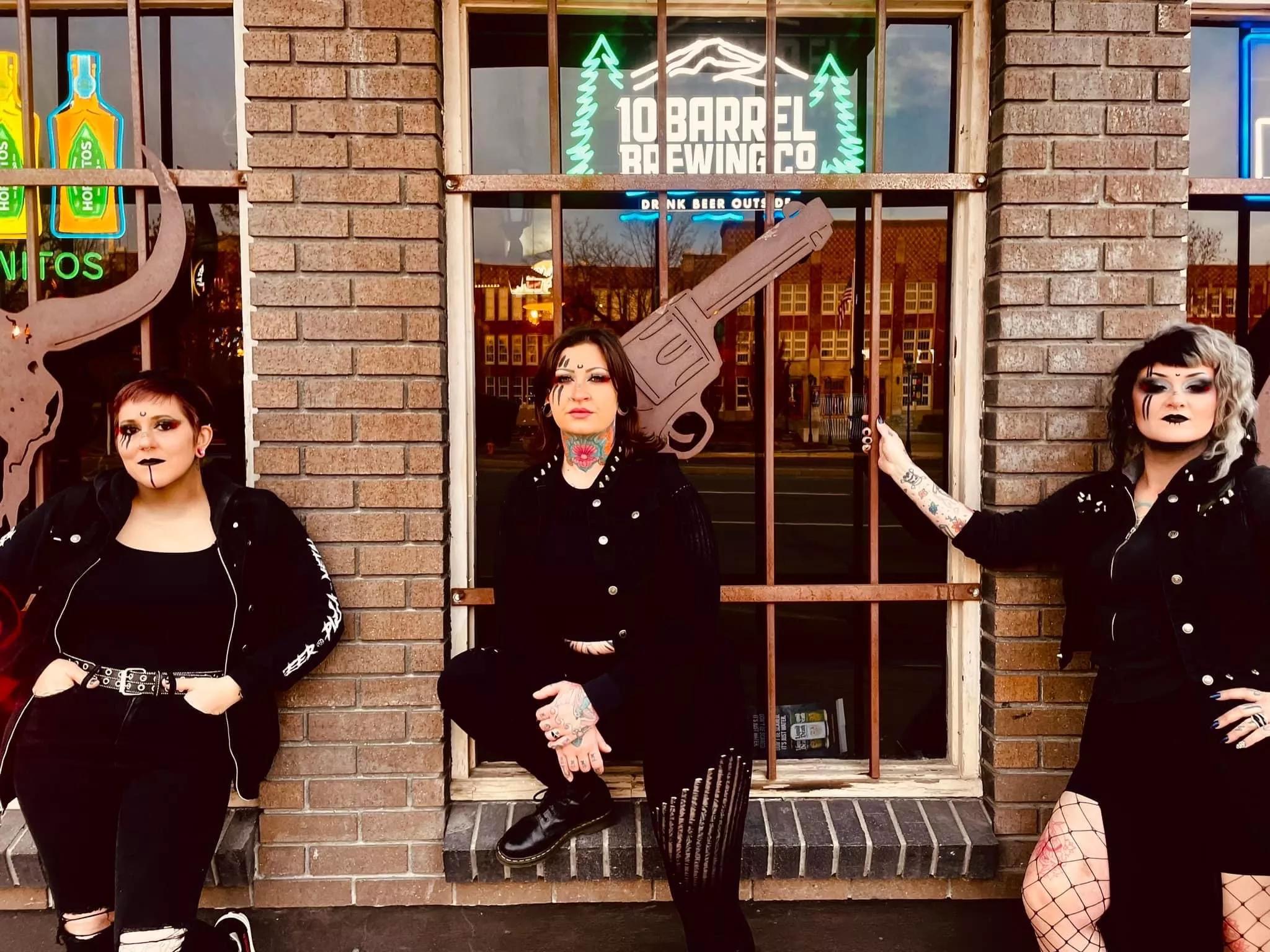 three women standing outside of a brick building with big windows