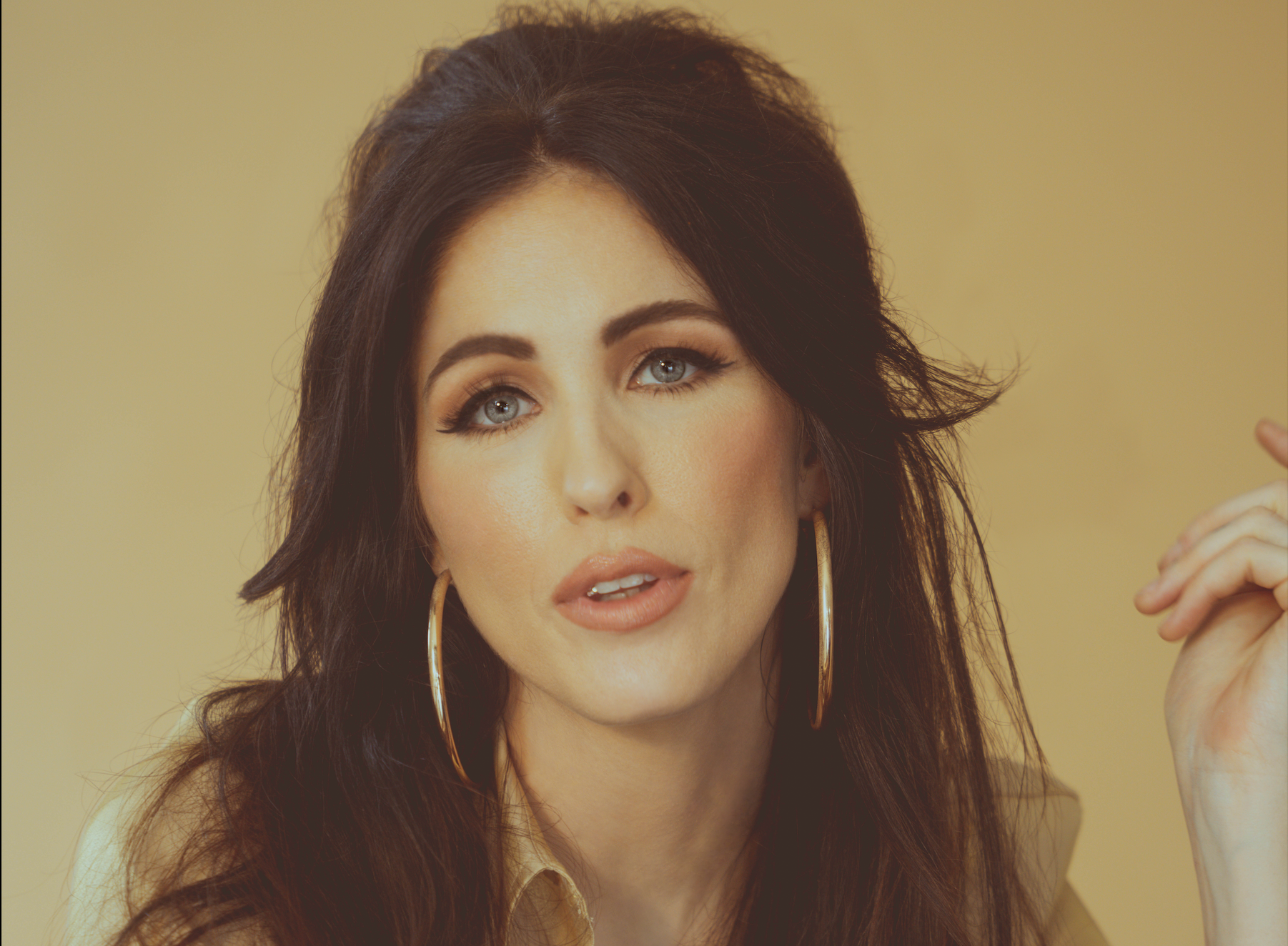 brunette woman wearing '60s makeup and hoop earrings