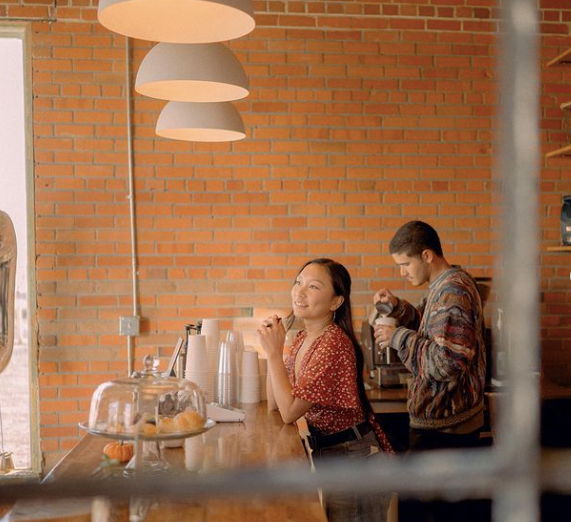 two people standing behind a counter in a coffee shop
