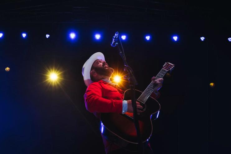 man in white hat and red shirt playing the guitar