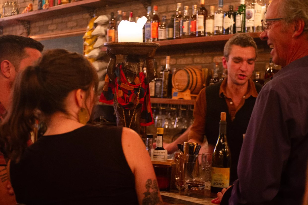people sitting at a bar talking to a bartender