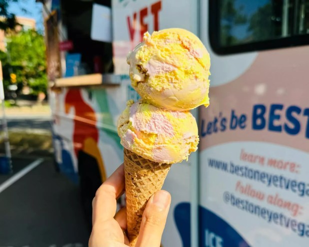 A person holding a vegan ice cream cone backdropped by Best One Yet's truck