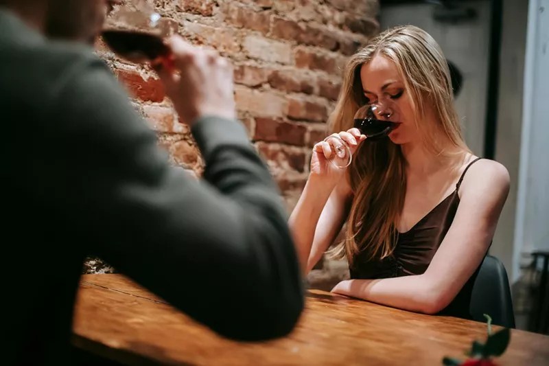 woman at table with man drinking red wine