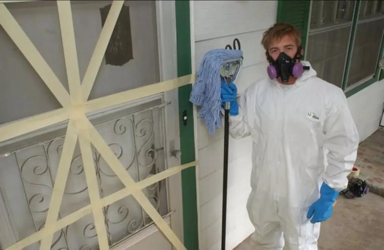 Man in rubber suit with gas mask and mop