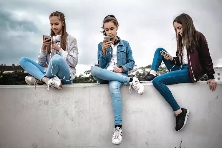 three teen girls on cell phones