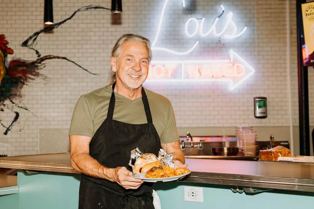 man in a black apron holding a plate of food