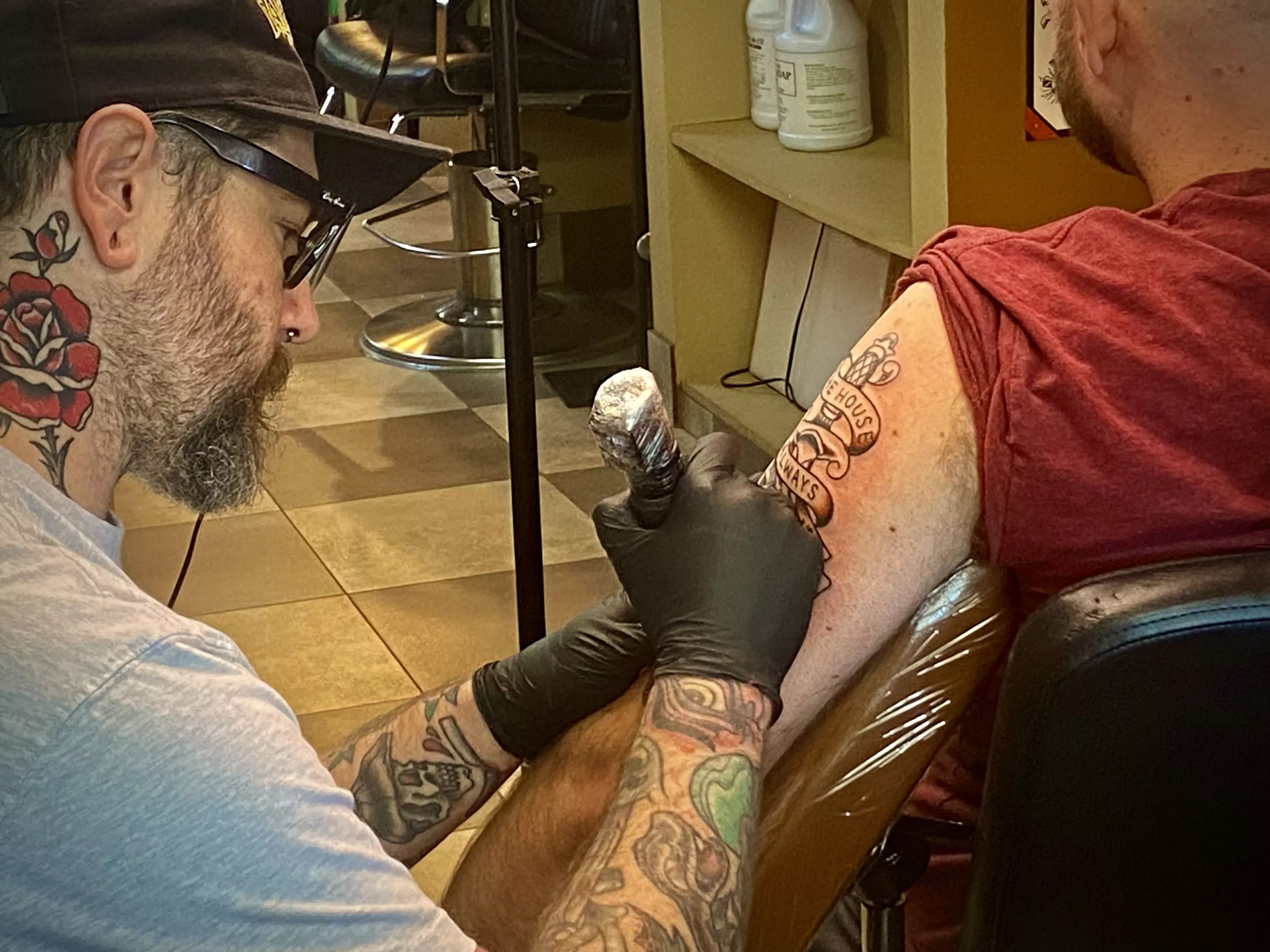 A man gives another man a tattoo