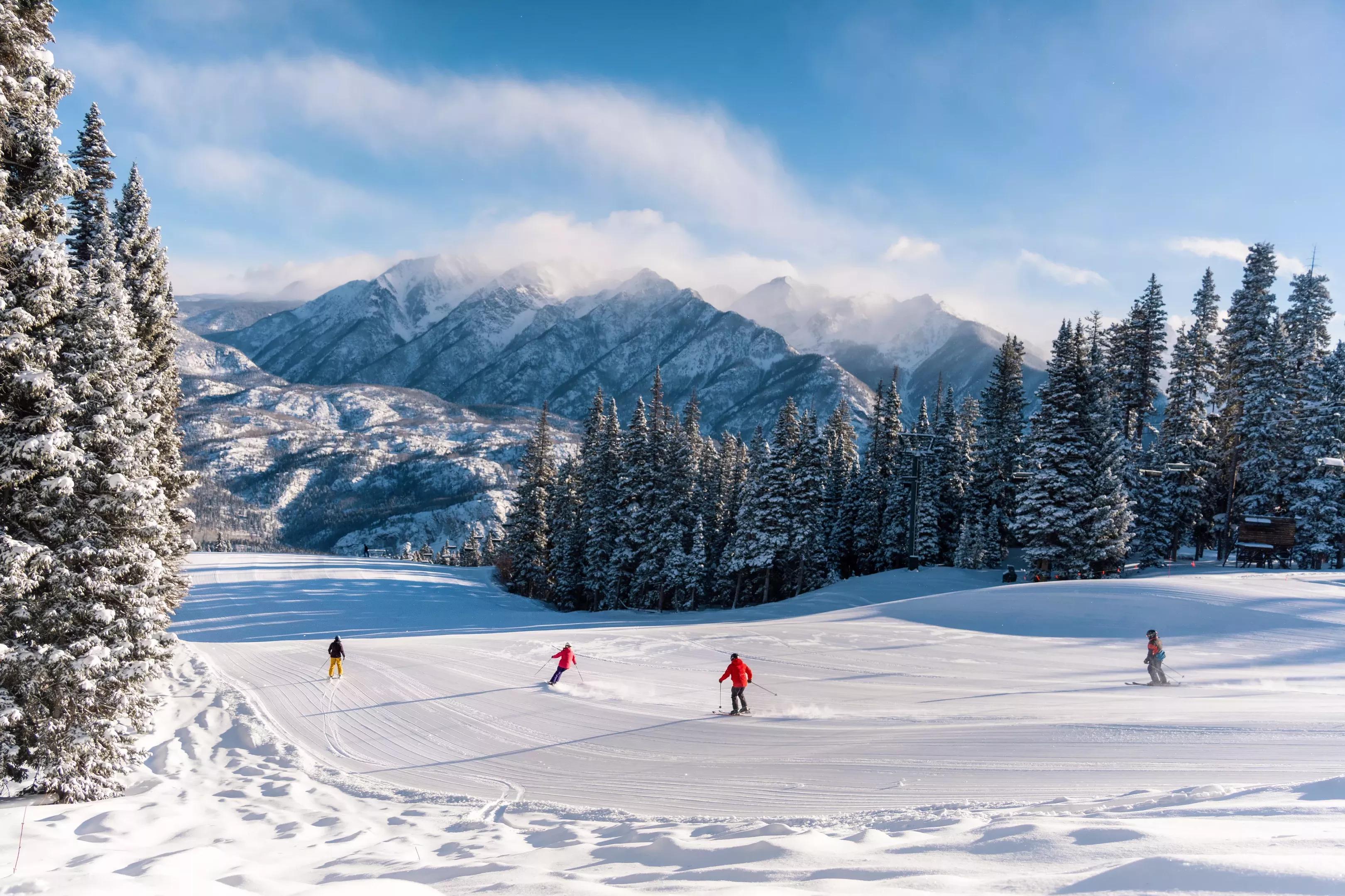 A group of people backdropped by mountains while skiing at Purgatory Resort