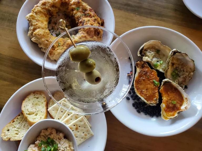 a martini and various foods on white plates