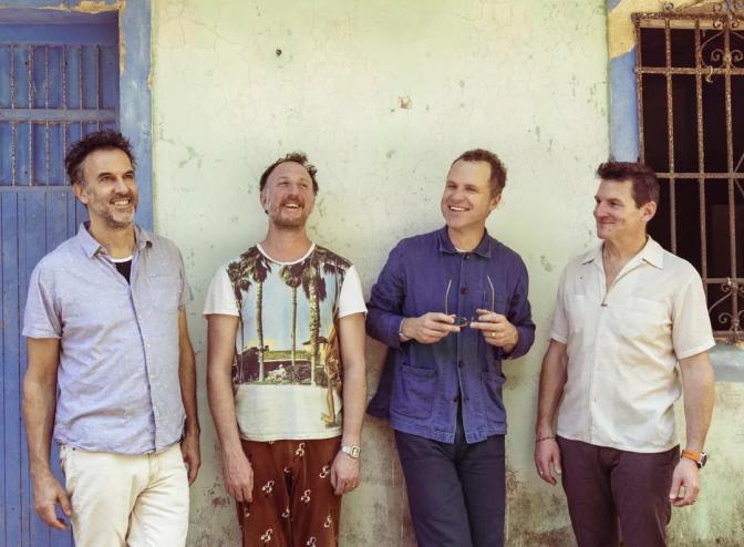members of the band guster lean against a wall