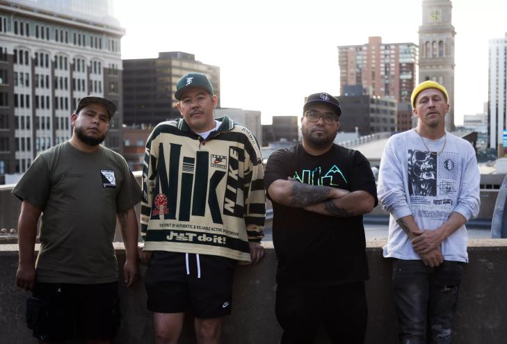 A group of men lean against a balcony.