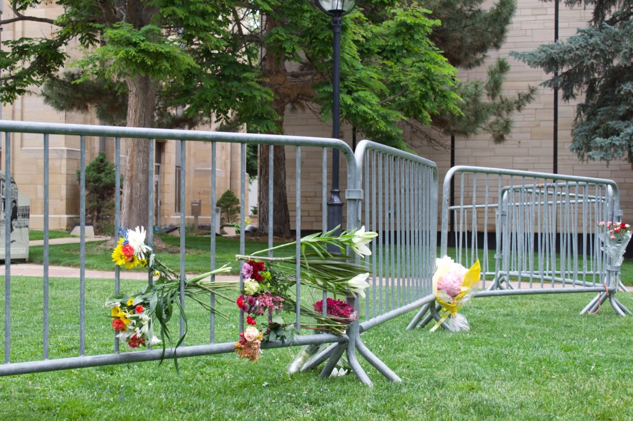 memorial flowers line a fence in the grass