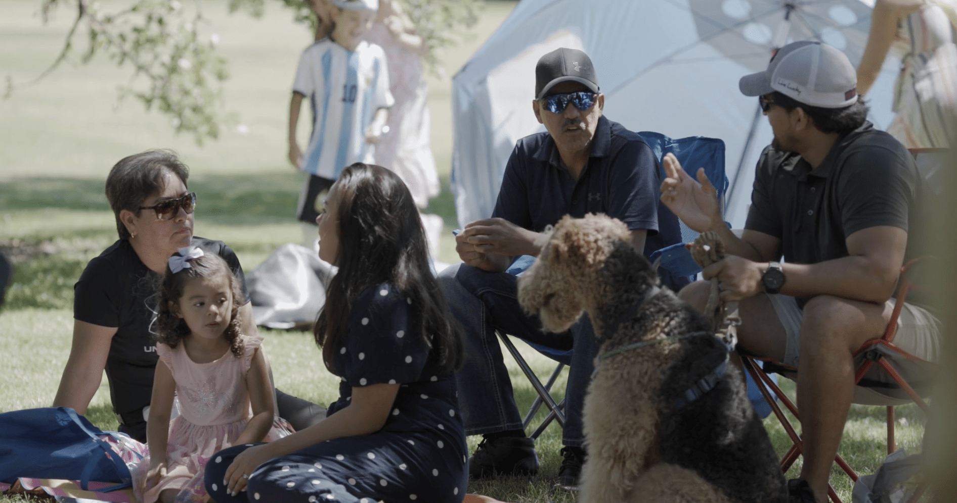 People and a dog sit together in the grass