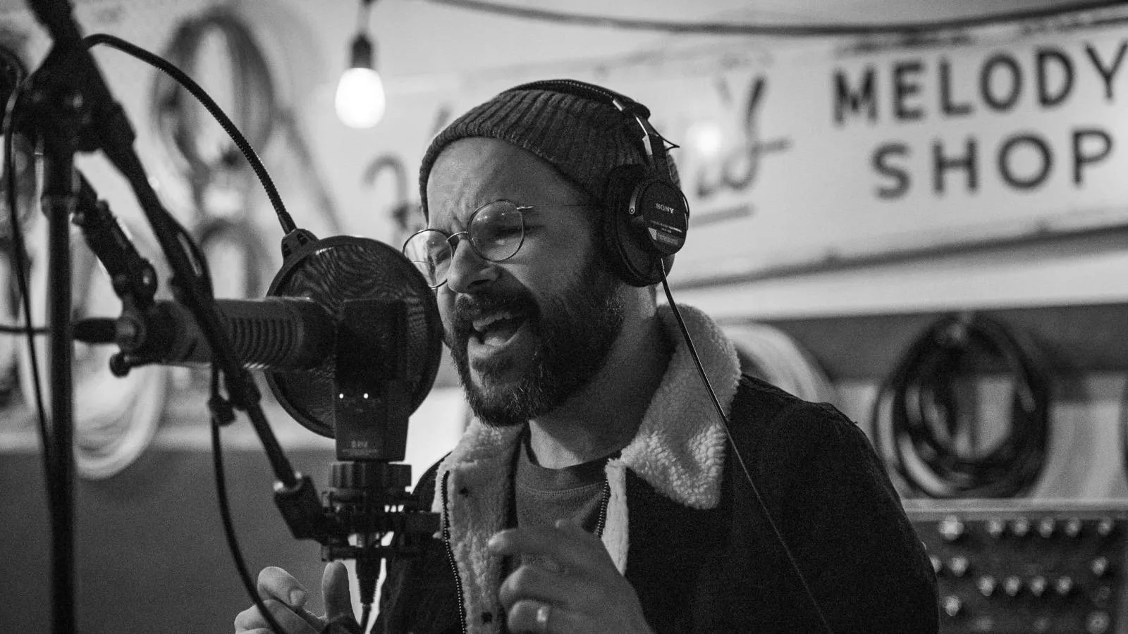 Denver-based musician Jem Zornow sings into a microphone in a recording studio.
