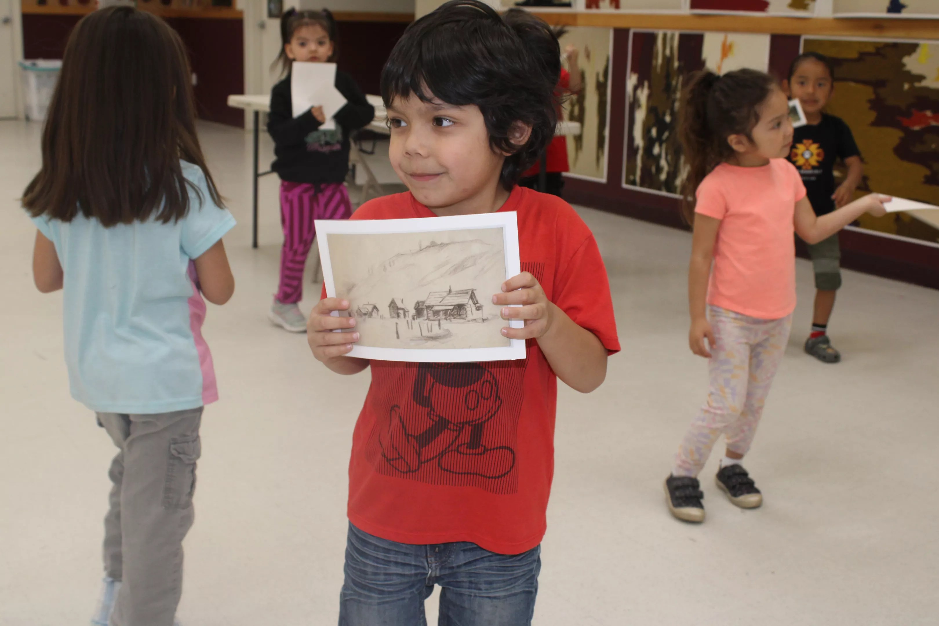 A young boy holds artwork
