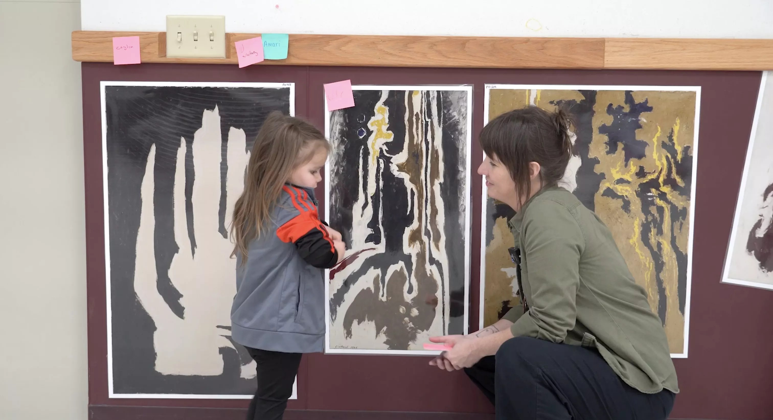 A young girl and an adult in front of artwork